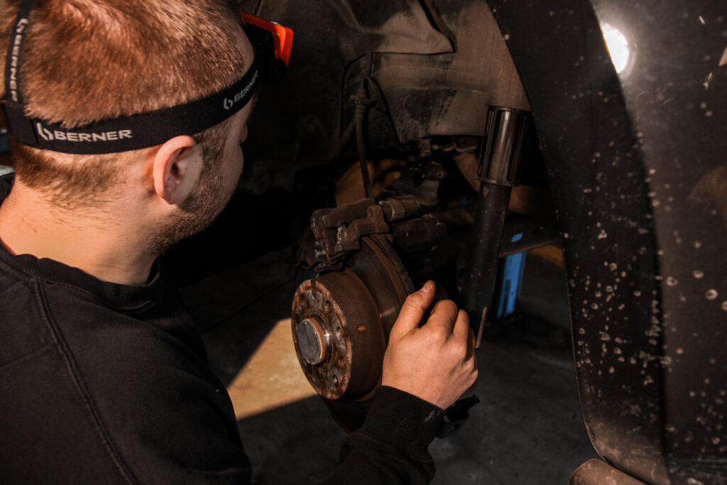 Mechanik w latarce czołowej naprawia zawieszenie i hamulce samochodu