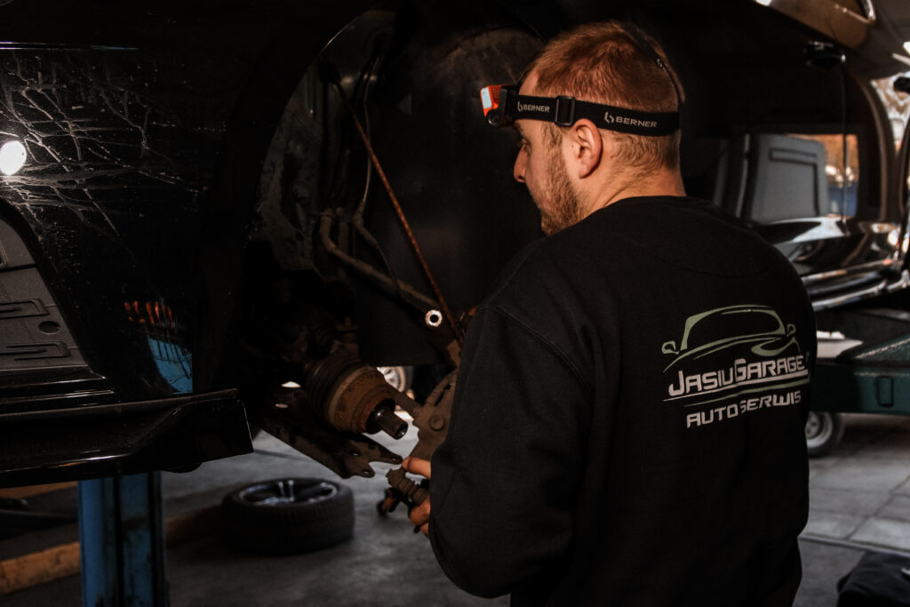 Mechanik Jasiu Garage przy naprawie zawieszenia auta na podnośniku