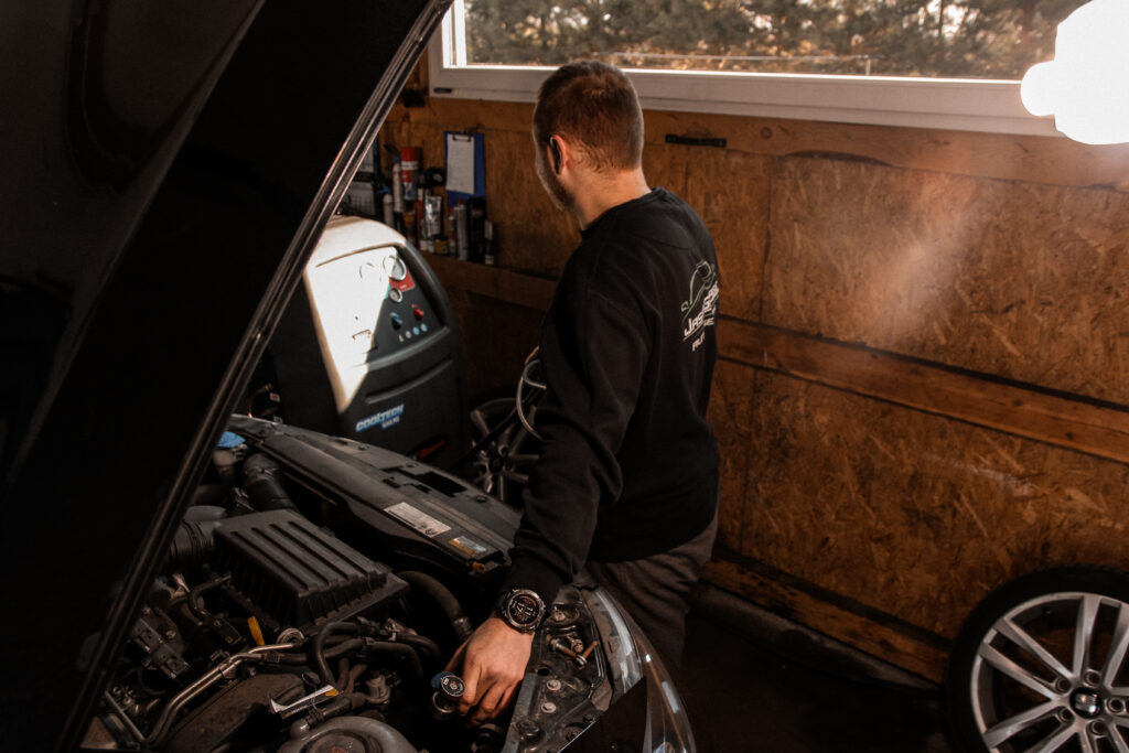 Mechanik Jasiu Garage przy silniku auta w warsztacie