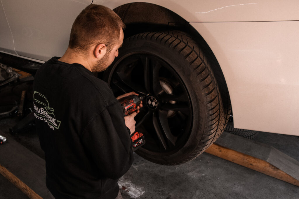 Mechanik odkręca koło kluczem udarowym podczas wymiany opon