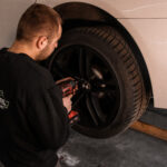 Mechanik odkręca koło kluczem udarowym podczas wymiany opon