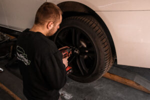 Mechanik odkręca koło kluczem udarowym podczas wymiany opon