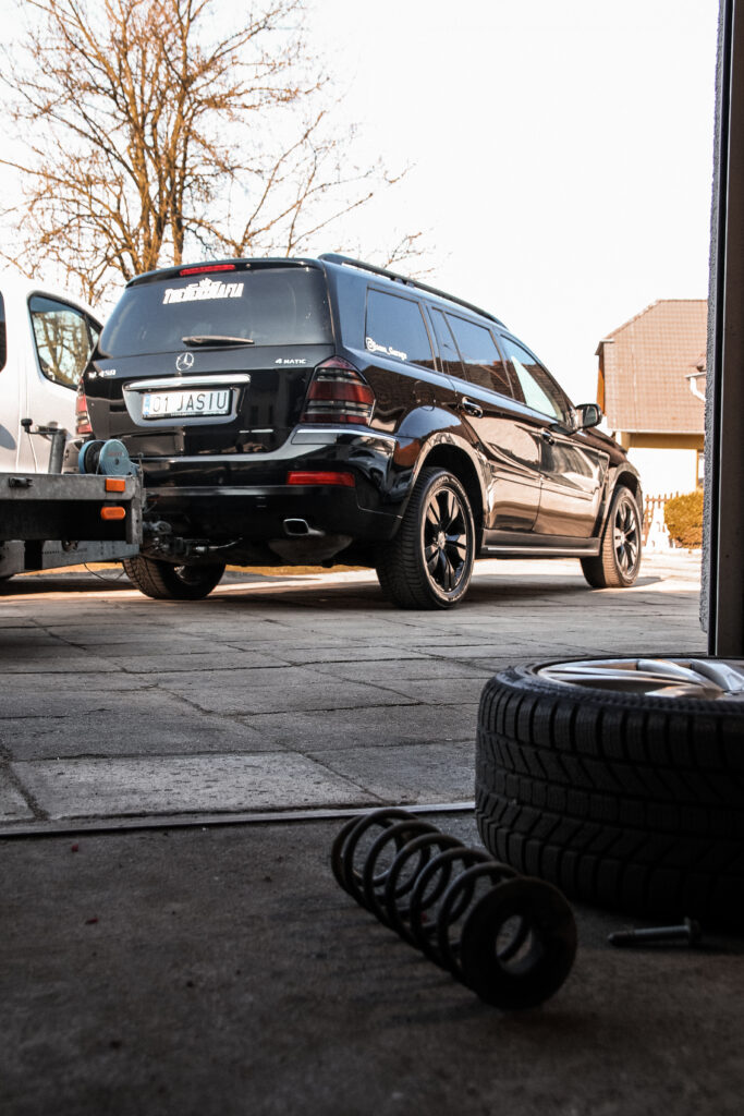 Mercedes GL przed warsztatem, na pierwszym planie opona i sprężyna zawieszenia
