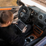 Mechanik konfiguruje auto testerem diagnostycznym we wnętrzu samochodu