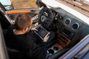 Mechanik konfiguruje auto testerem diagnostycznym we wnętrzu samochodu